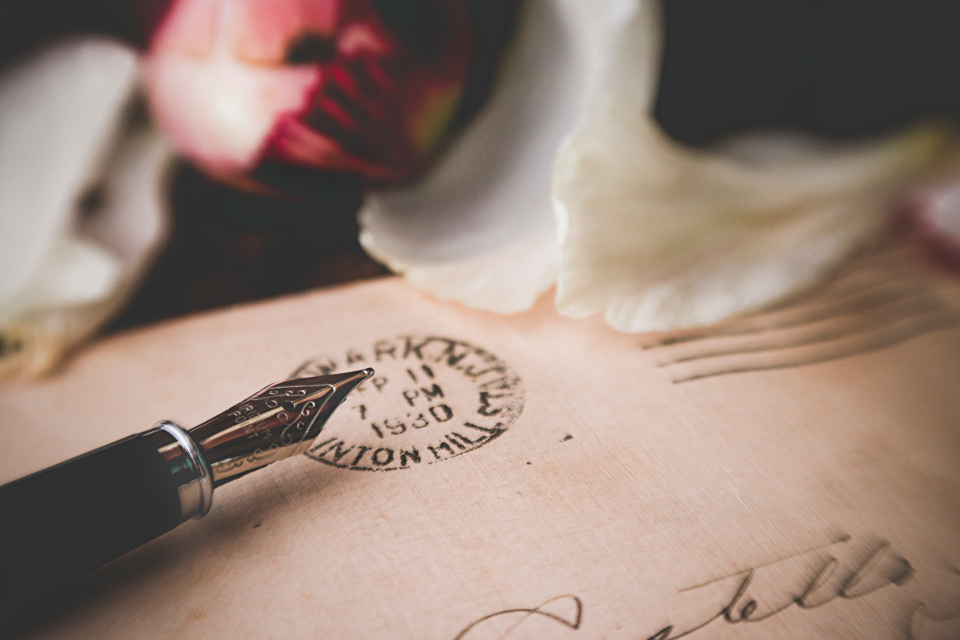A fountain pen resting on an old handwritten envelope with a postmark