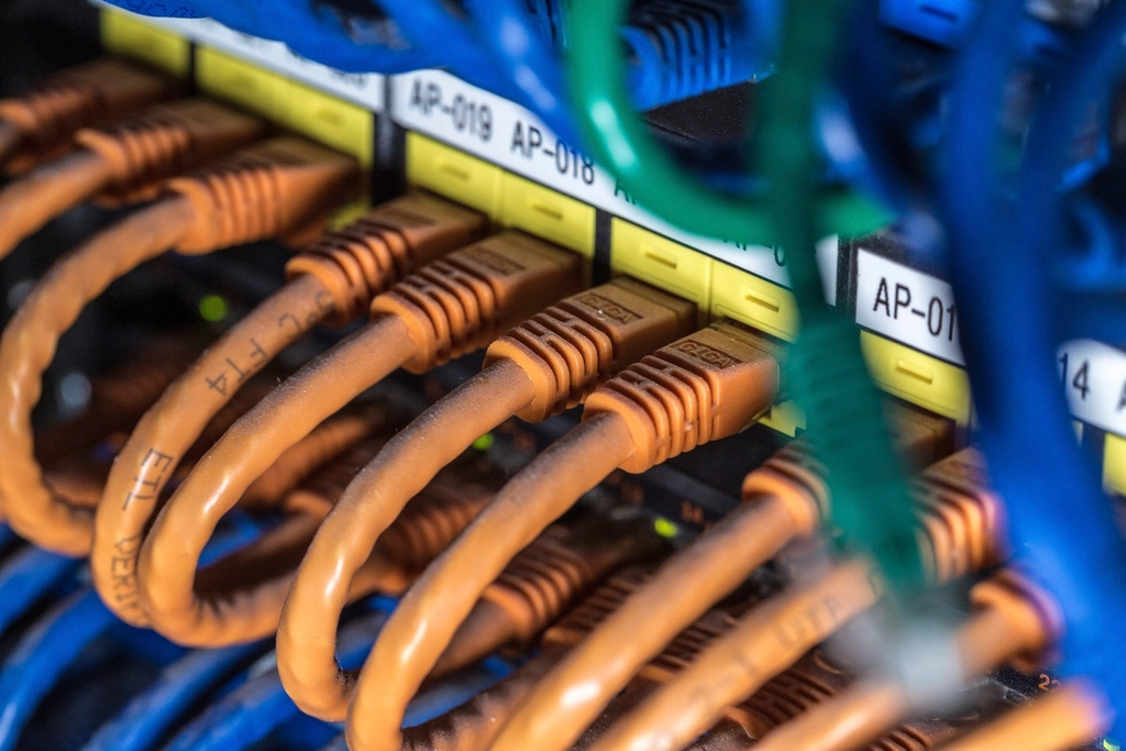 Orange and blue network cables plugged into a server rack